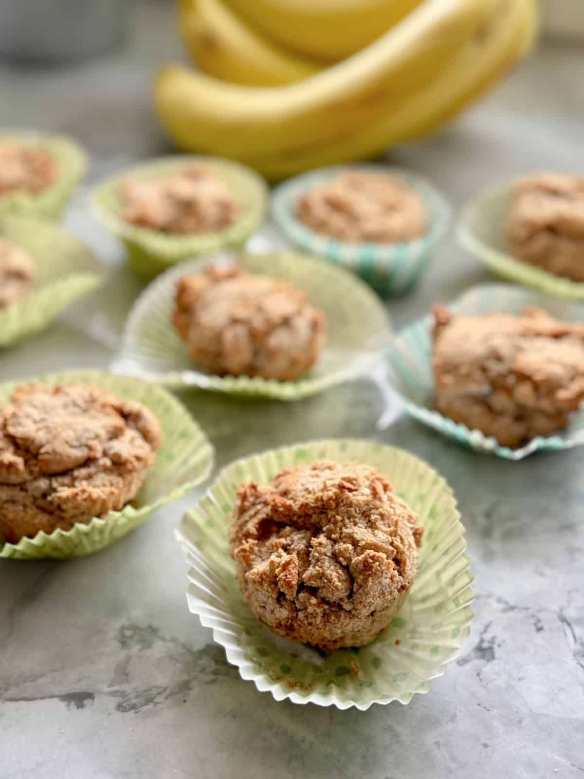 Multiple muffins out of their wrappers on a marble countertop.