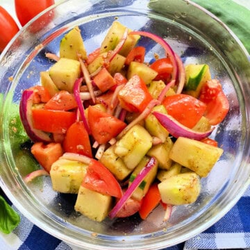 Glass bowl filled with Cucumber tomato onion salad .