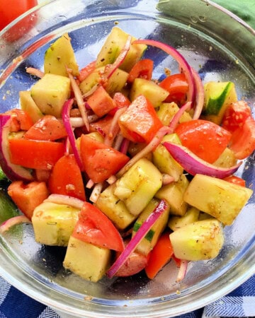 Glass bowl filled with Cucumber tomato onion salad .