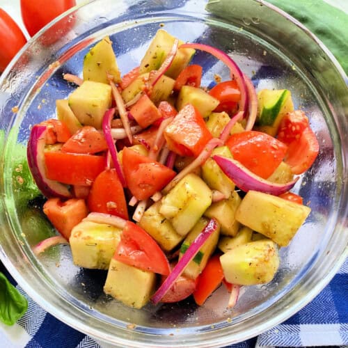 Glass bowl filled with Cucumber tomato onion salad .