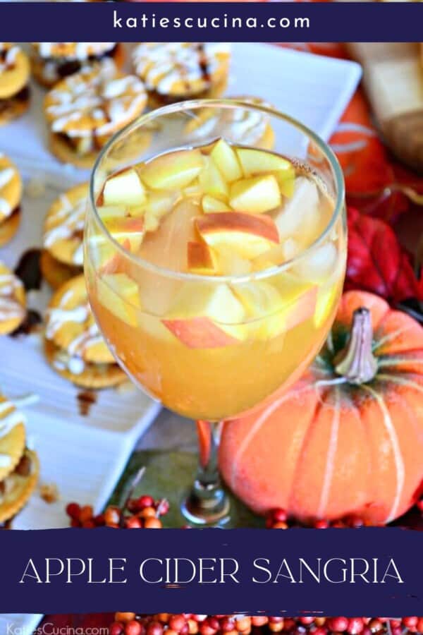 Wine glass filled with sangria and diced apples with text on image for Pinterest.