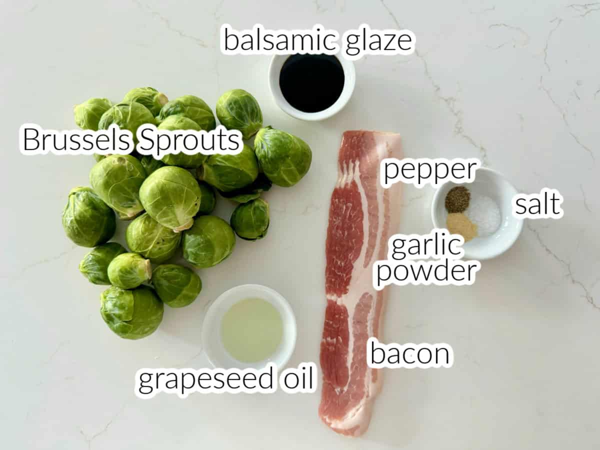 Brussels sprouts, balsamic glaze, bacon, grapeseed oil, garlic powder, pepper, salt on a white countertop.