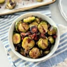 White bowl filled with roasted brussels sprouts on a cloth.