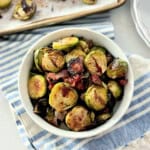 White bowl filled with roasted brussels sprouts on a cloth.