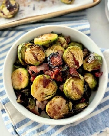 White bowl filled with roasted brussels sprouts on a cloth.