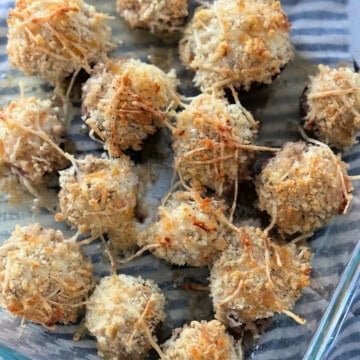 Glass dish filled with baked stuffed mushrooms.