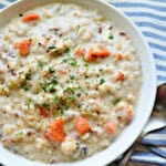 White bowl filled with cream of chicken soup on a blue and white striped cloth.