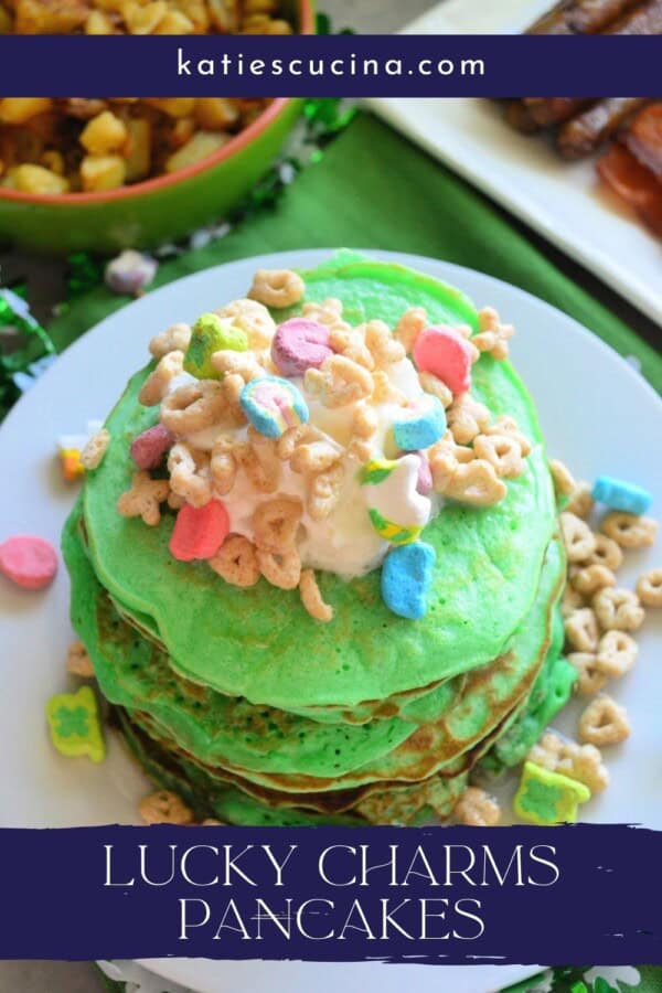 Stacked pancakes with whipped cream and lucky charms cereal on top with text on image for Pinterest.