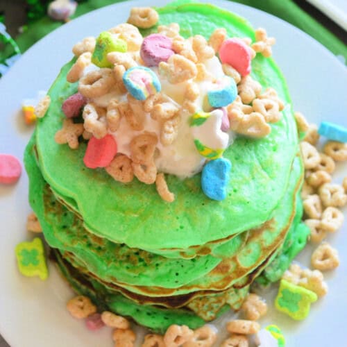 Green stacked pancakes with whipped cream and lucky charms.
