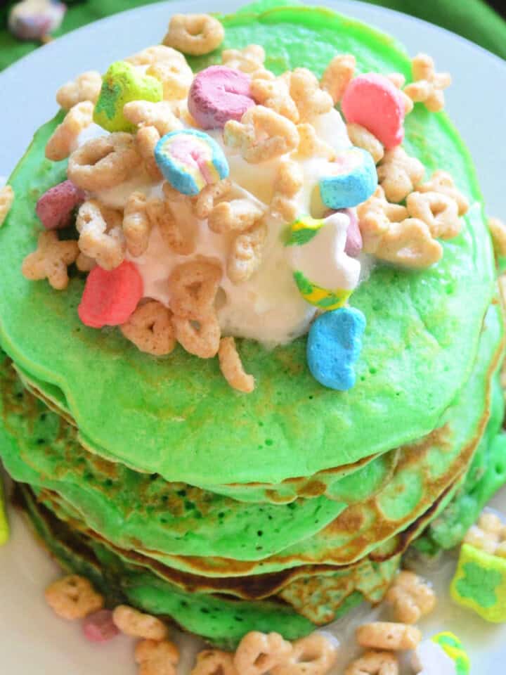Green stacked pancakes with whipped cream and lucky charms.