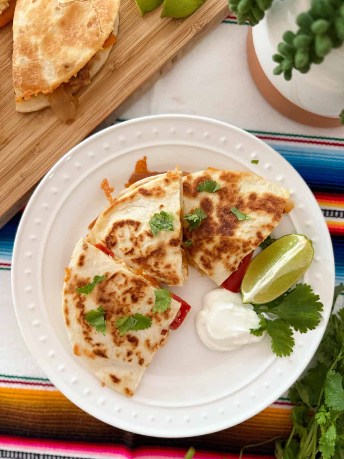 3 slices of quesadilla with sour cream and lime wedges.
