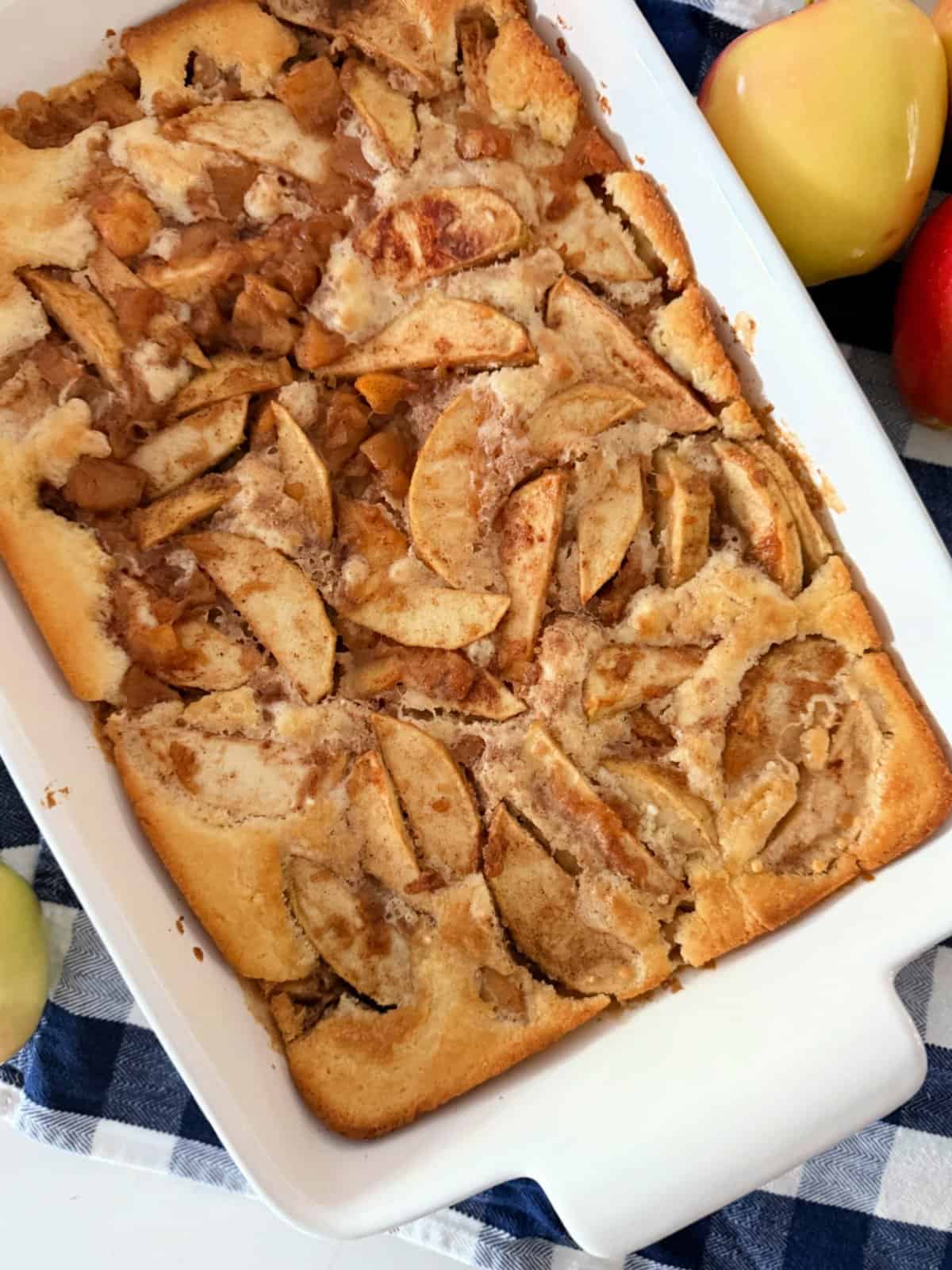 Apple cobbler baked in a white dish on a blue and white checkered cloth.
