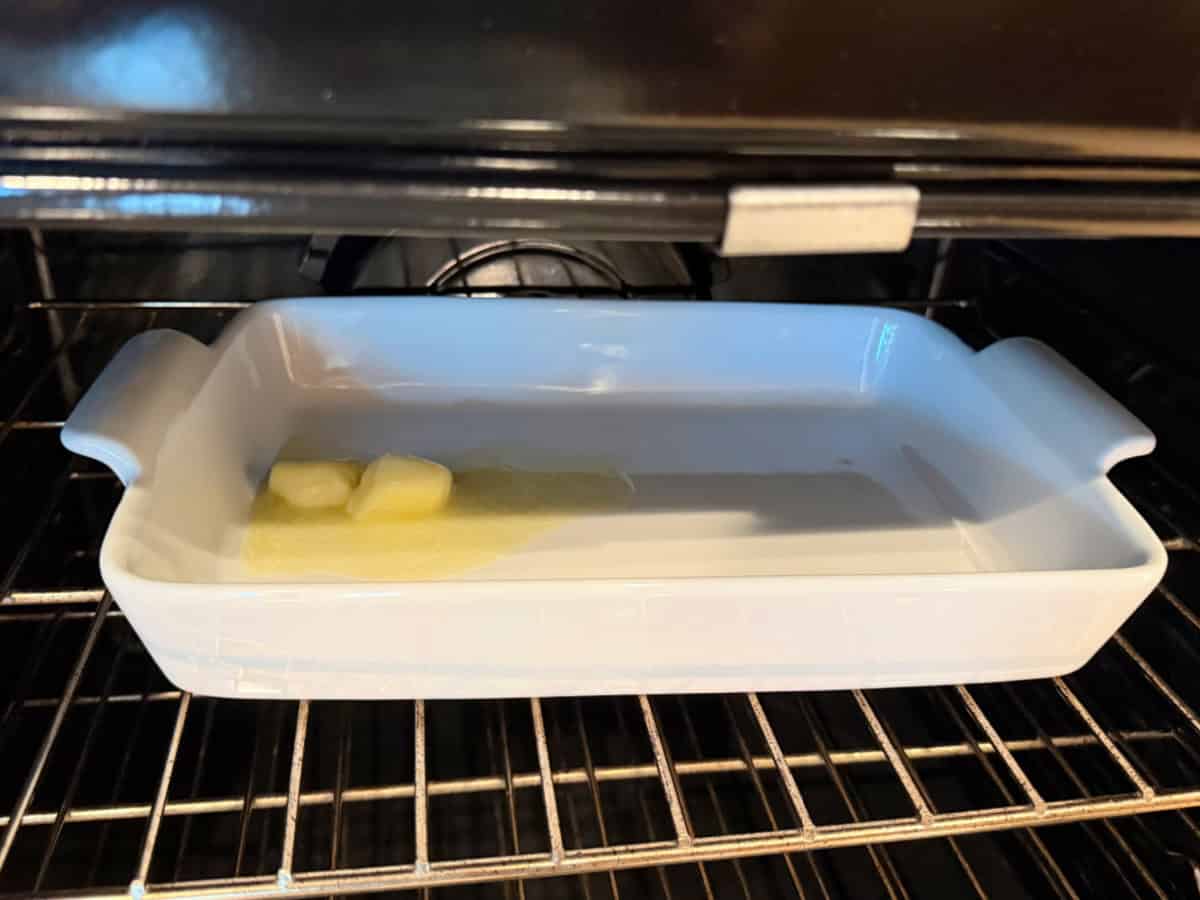 White baking dish in the oven with butter melting in dish.