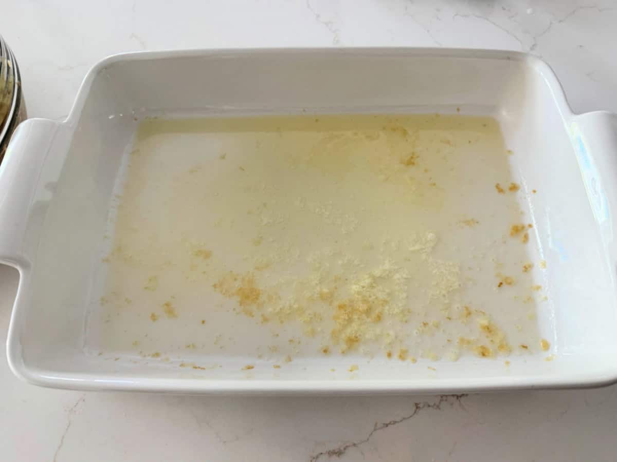 White baking dish filled with melted brown butter on a white marble countertop.