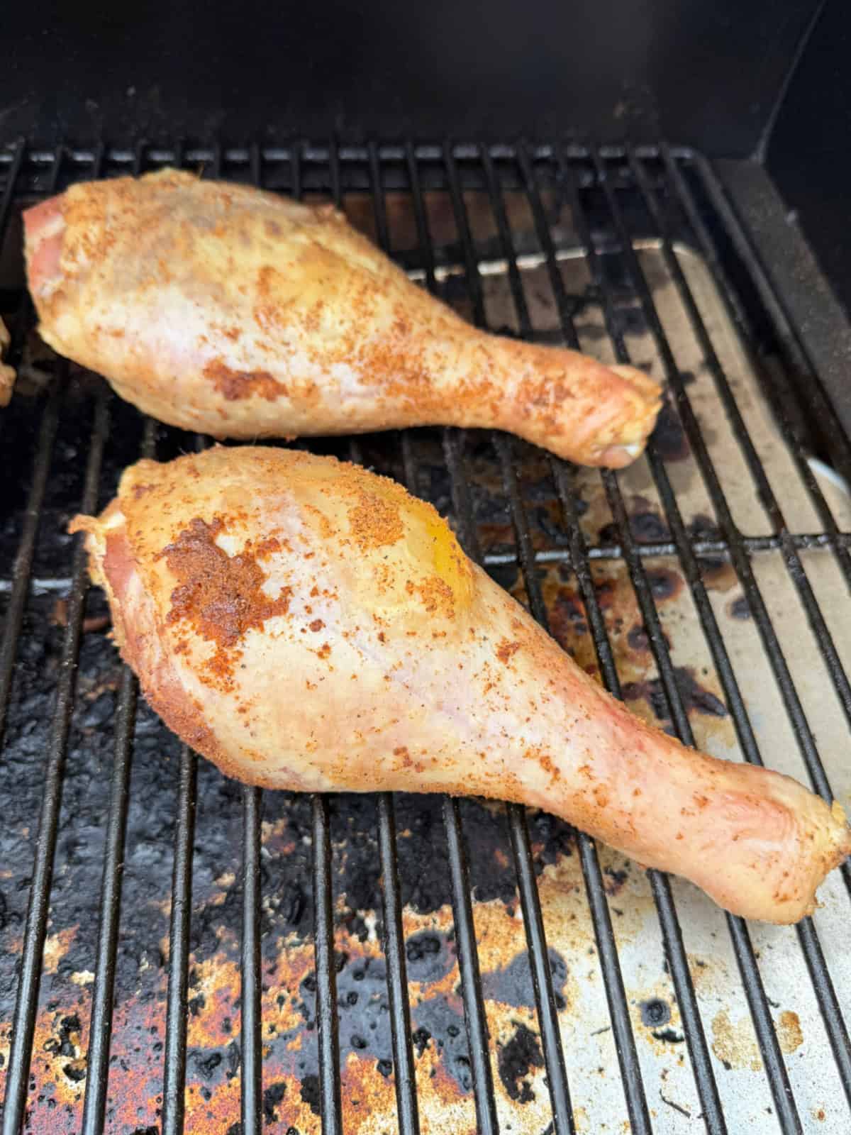 Two raw turkey legs on a grill.