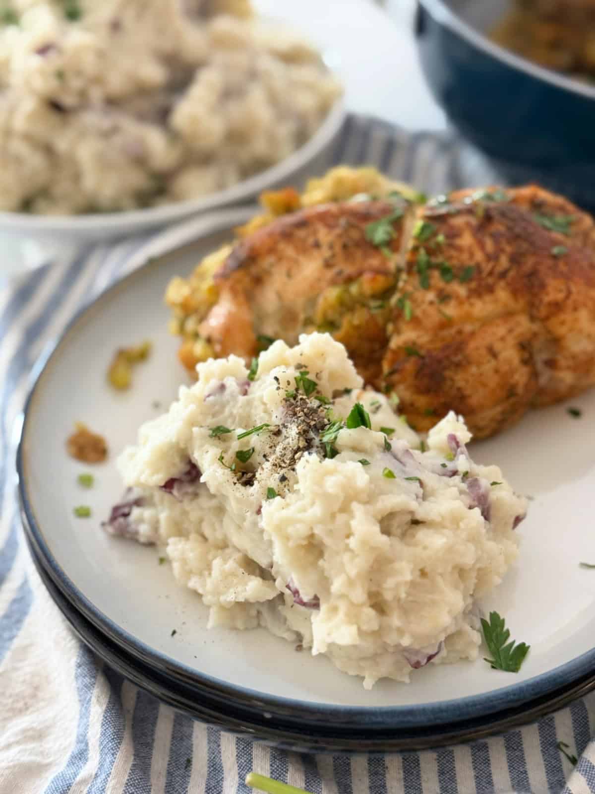 Double stacked plate with red skinned mashed potatoes and chicken breast.