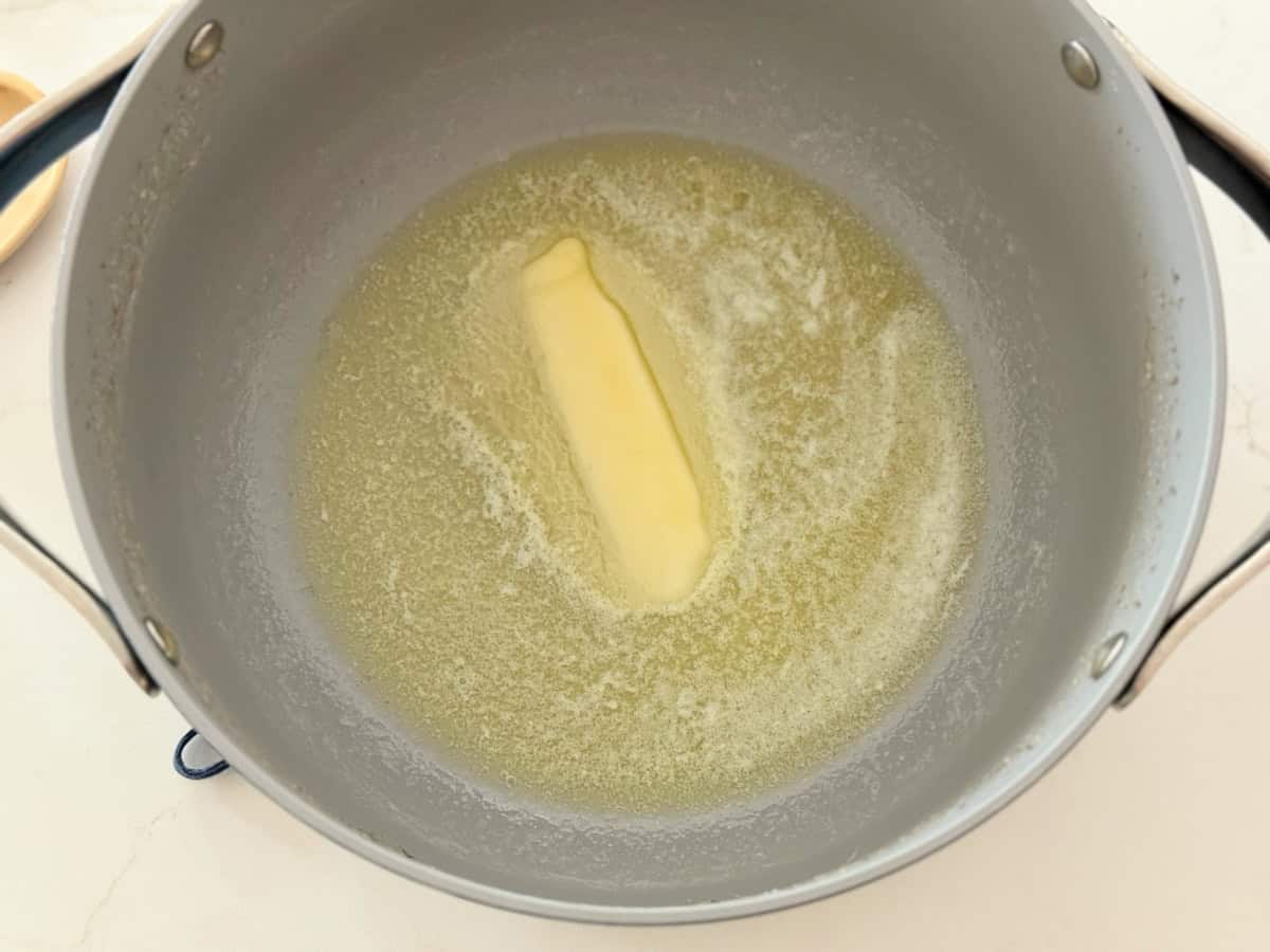 Large pot with melted stick of butter on a white countertop.