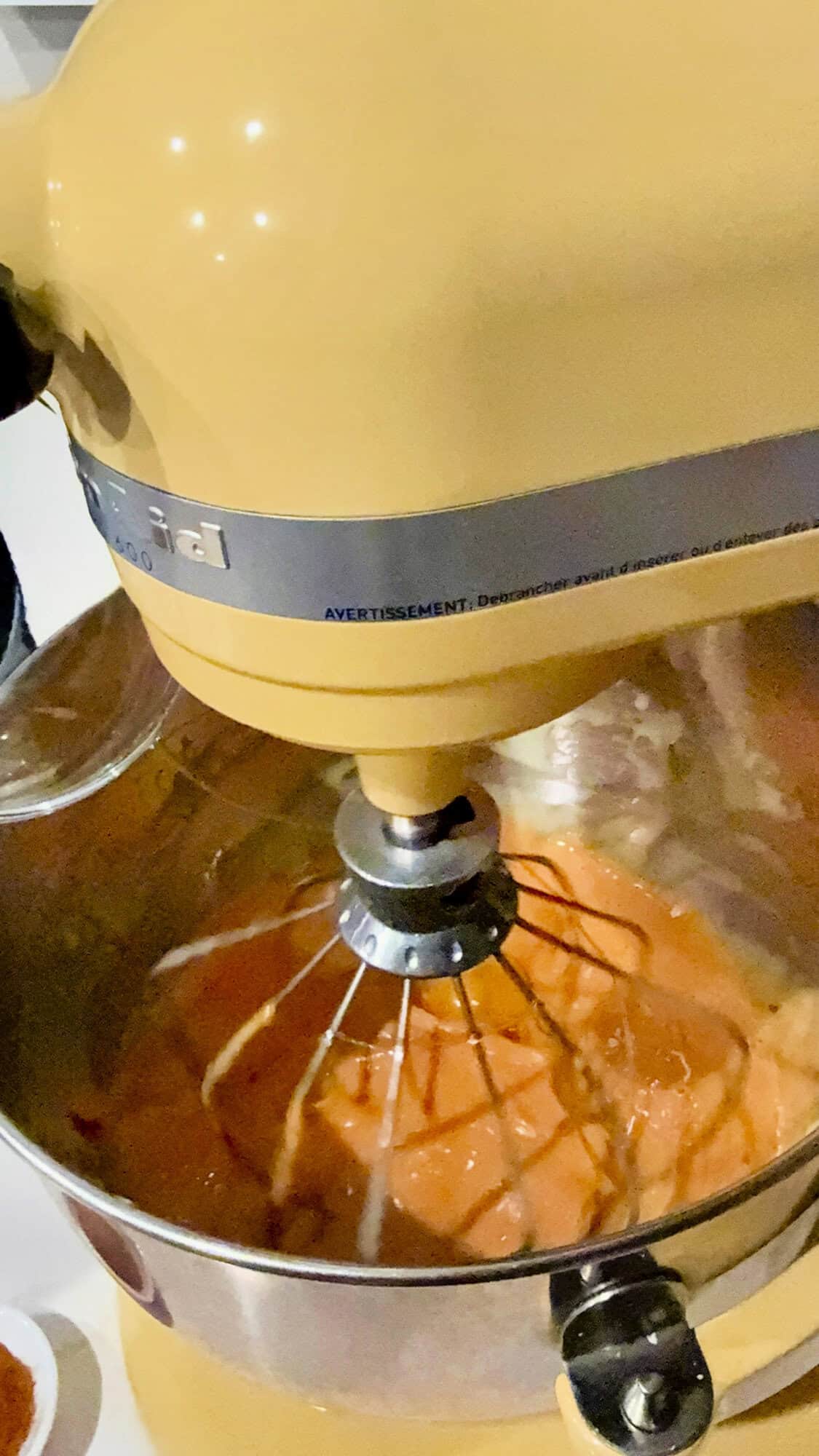 Yellow KitchenAid Mixer with orange mixture.