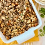 White rectangular dish filled with stuffing on top of a yellow cloth.