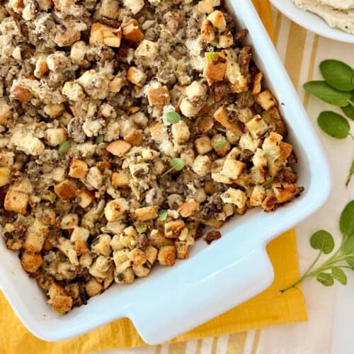 White rectangular dish filled with stuffing on top of a yellow cloth.