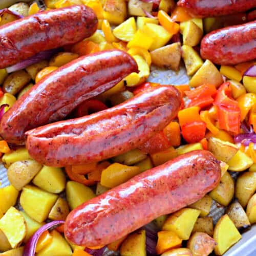 Four sausage links on a bed of potatoes and peppers layered on a sheet pan.
