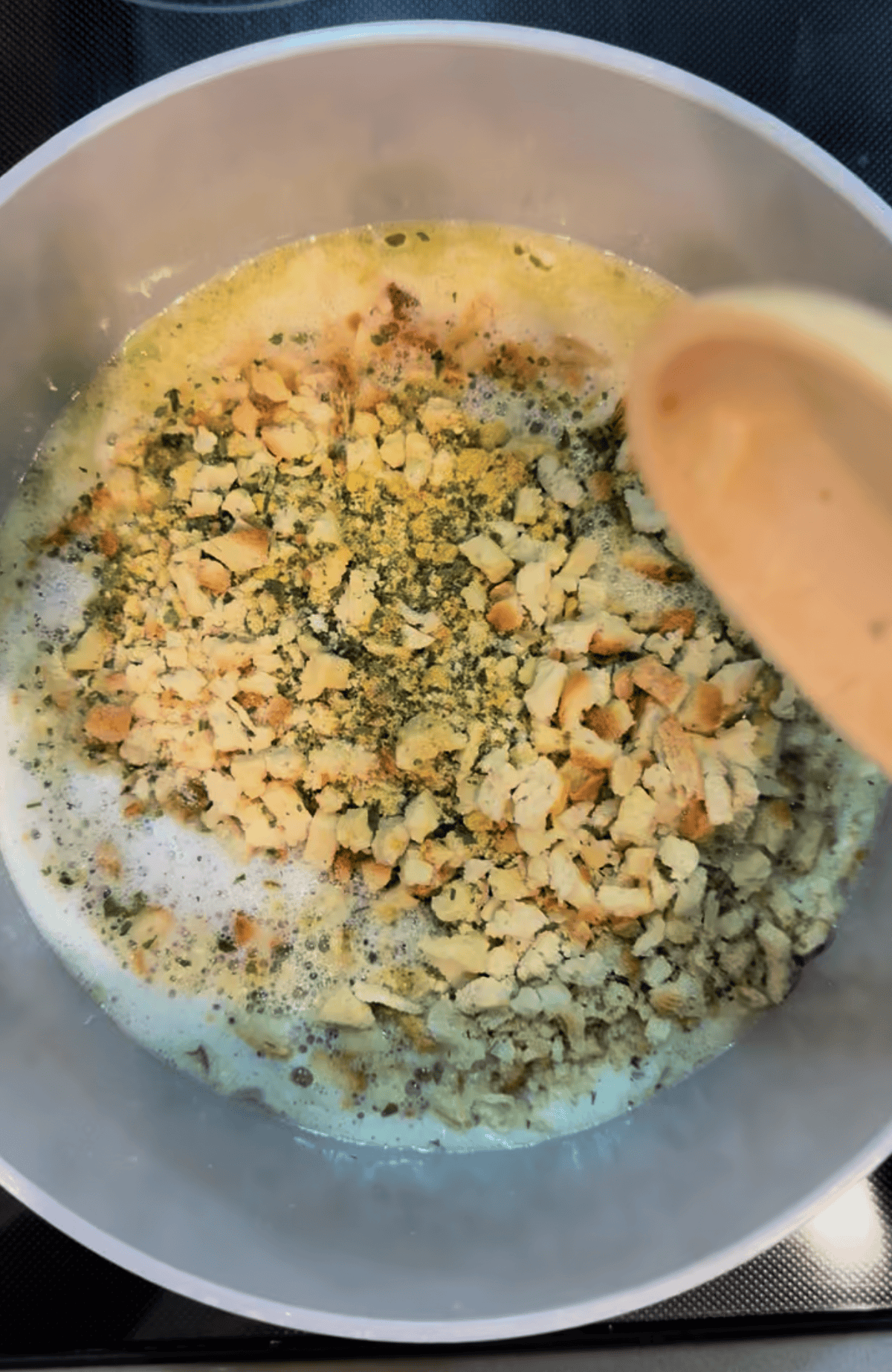 Gray pot filled with cubed stuffing mix with wood spoon on the side of the pot.