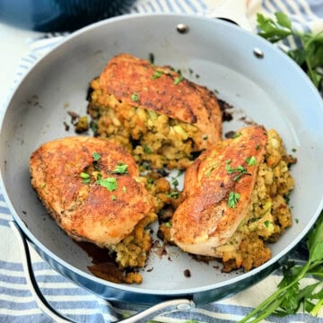 Three chicken breast roasted with stuffing inside them in a blue frying pan.