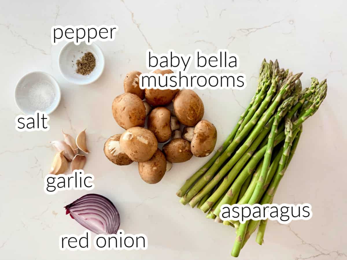 Ingredients on counter: salt, pepper, baby bella mushrooms, asparagus, red onion, and garlic.