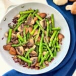 Grey frying pan with quartered cooked mushrooms and asparagus.